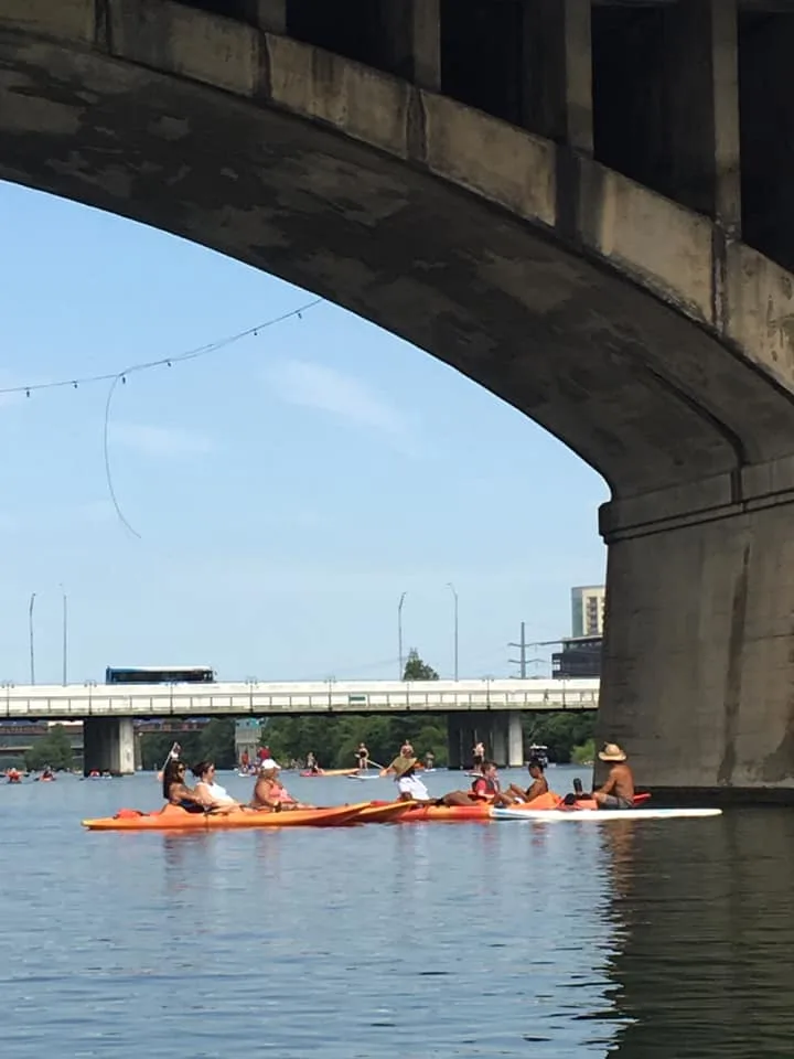 Kayakers passing beneath a bridge on Lady Bird Lake in Austin